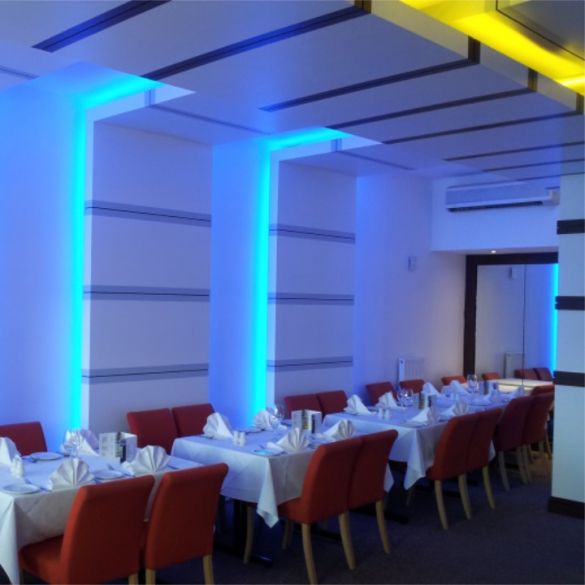 Ceiling and wall in restaurant illuminated by blue and yellow coloured LED linear strip lighting